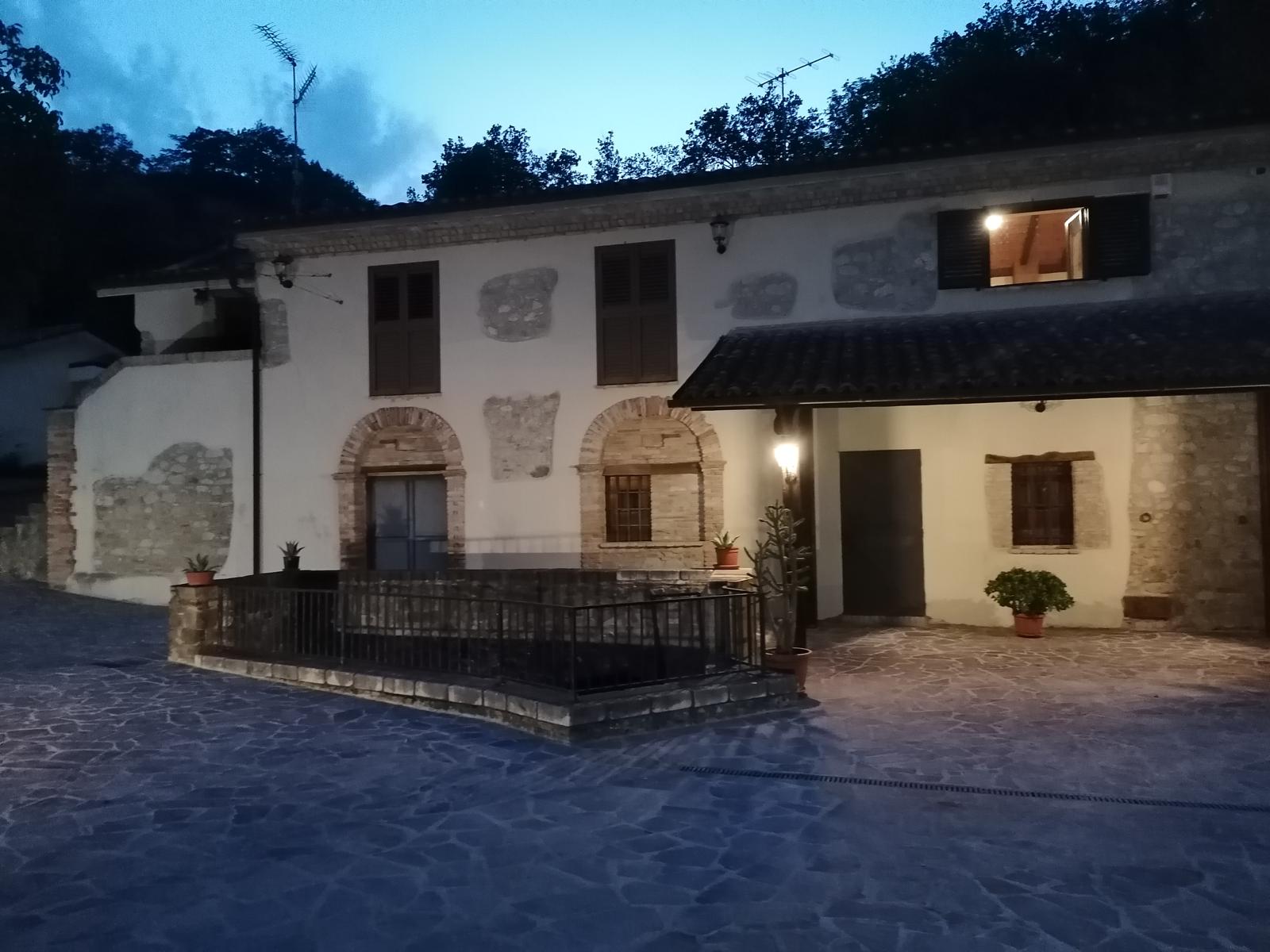 Facciata del Mulino Brandolini illuminata di sera con muri in pietra e archi